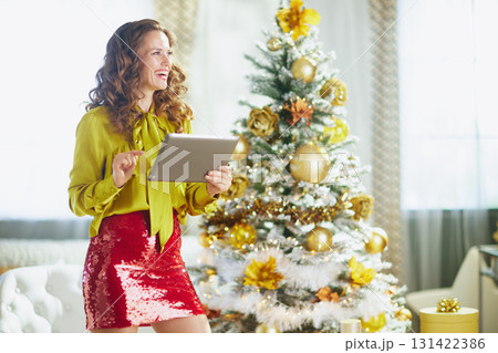 Fashionable Woman with Tablet by a Christmas Tree Fashionable Woman with Tablet by a Christmas Tree 131422386