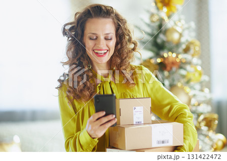 Cheerful Woman with Holiday Packages and Smartphone 131422472