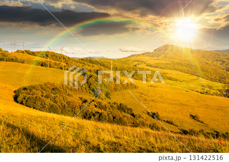 countryside mountain landscape in autumn at sunset. rural field on green hills. beautiful scenery with grassy meadows and forested slopes in highland under blue sky. scenic view in evening light 131422516