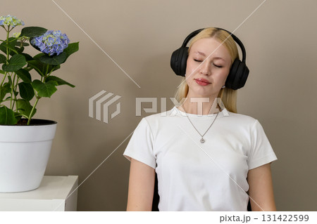 Woman enjoying music in headphones with eyes closed at home Woman enjoying music in headphones with eyes closed at home 131422599