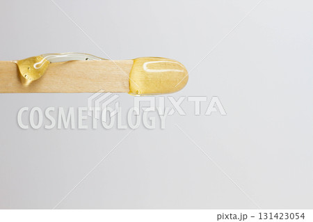The inscription cosmetology on a wooden spatula with wax for hair removal. 131423054