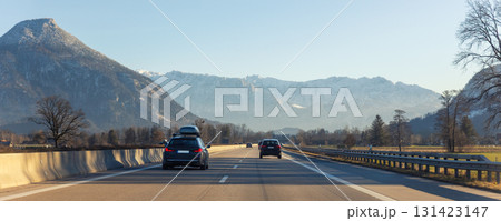Scenic view cars driving mountain alpine highway road cold sunny winter day at Europe mountain resort. Winter holidays season travel skiing. Vacation transport road peaks background 131423147