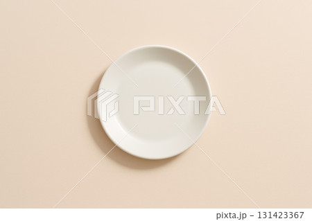 Empty white plate on soft beige background, minimalistic design, top view. Empty white plate on soft beige background, minimalistic design, top view. 131423367