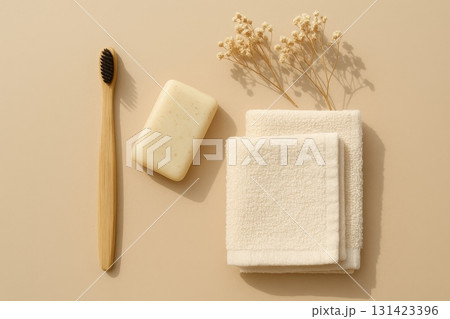 Natural bathroom essentials with bamboo toothbrush, soap, towels, and dried flowers on beige background. 131423396