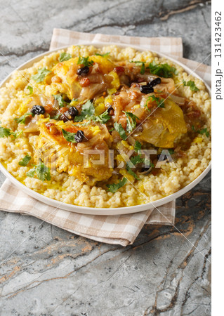 Chicken and Tfaya Couscous is a classic Moroccan dish in which tender couscous is topped with braised chicken and caramelized onion and raisin sauce closeup on the plate. Vertical Chicken and Tfaya Couscous is a classic Moroccan dish in which tender couscous is topped with braised chicken and caramelized onion and raisin sauce closeup on the plate. Vertical 131423462
