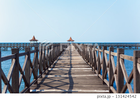 Long wooden pier with traditional gazebos - bale stretches over calm turquoise sea under clear blue sky. Perfect place for viewing amazing landscape.  Scenery for travel, resort, summer vacation 131424542