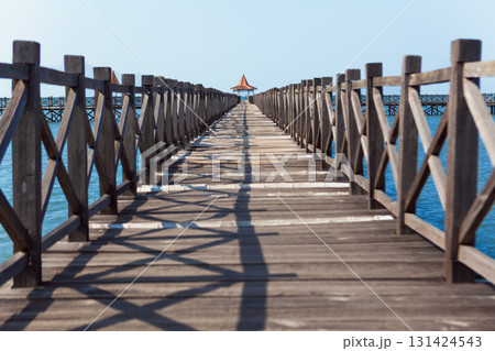Long wooden pier with traditional gazebos - bale stretches over calm turquoise sea under clear blue sky. Perfect place for viewing amazing landscape.  Scenery for travel, resort, summer vacation 131424543