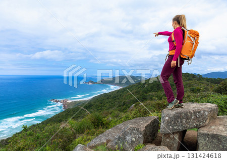 Sporty woman hikes coastal mountain trail with backpack view 131424618