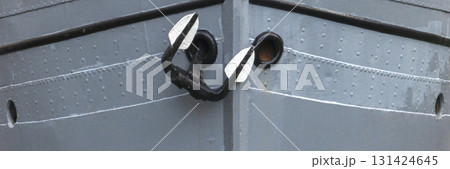Close-up view of a ships steel hull with a traditional anchor secured at the bow.  131424645