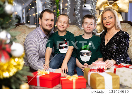 Portrait of happy family with two children celebrating Christmas next to Christmas tree Portrait of happy family with two children celebrating Christmas next to Christmas tree 131424650
