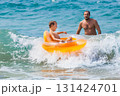 Happy kid with father have fun in sea surf on beach. Joyful child on inflatable ring ride on breaking wave. Travel lifestyle, swimming activities in family summer camp. Vacations on tropical island 131424701