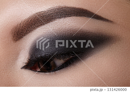 Macro beauty closeup of woman eye with intense smoky shadows and smudged eyeliner. Perfect for gothic fashion, Halloween makeup, club party style and dramatic artistic visuals 131426000