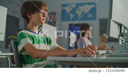 Young Student Striped T-shirt Working at Computer in Bright Classroom Young Student Striped T-shirt Working at Computer in Bright Classroom 131426090