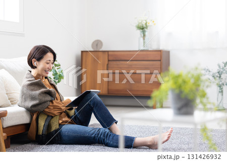 ワイヤレスイヤホンをつけてタブレットを使用するミドル女性 ワイヤレスイヤホンをつけてタブレットを使用するミドル女性 131426932