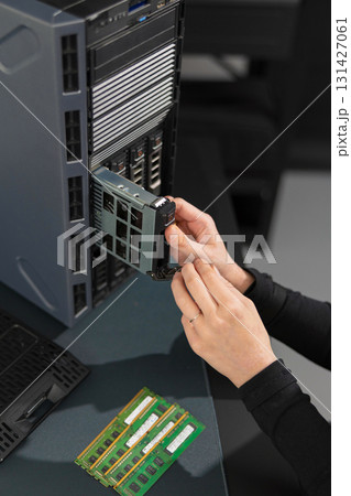 Female IT technician installs PCIe expansion card into server rack during maintenance and upgrade Female IT technician installs PCIe expansion card into server rack during maintenance and upgrade 131427061