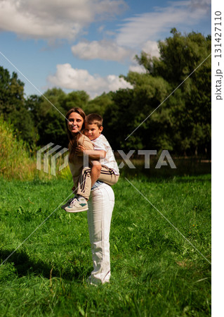 Adorable mother-son duo playing dancing joyfully outside in park. Pure happiness and playful bonding. Candid family moment. 131427110