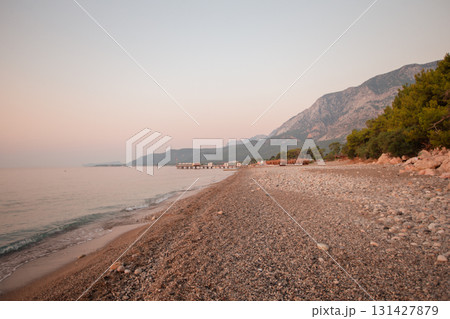 Calm morning landscape of pebble sand beach sea and mountains. 131427879