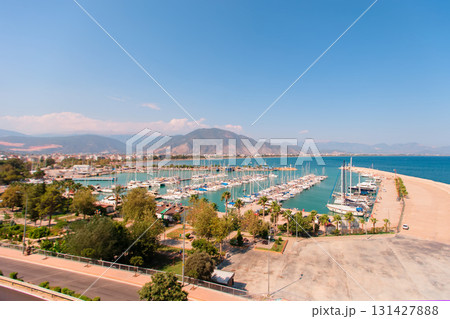 Coastal city view from above. Embankment with yachts and bay. Mountains are visible in the distance. 131427888