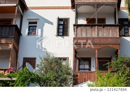 Part of a Greek architectural house with a white facade and wooden windows and balconies. Part of a Greek architectural house with a white facade and wooden windows and balconies. 131427894