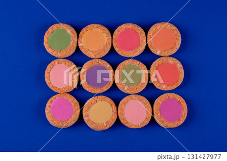 A row of colorful cookies with a blue background. The cookies are in a row and are of different colors 131427977