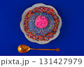 On the plate is a plate with a blue background and a pink glazed donut with sprinkles on top. A gold spoon is next to the plate 131427979