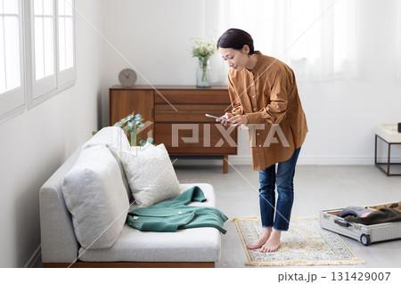 服をスマートフォンで撮影する女性 131429007