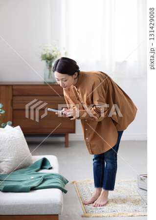 服をスマートフォンで撮影する女性 131429008