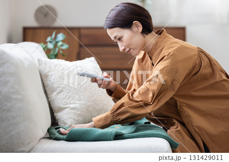 服をスマートフォンで撮影する女性 131429011