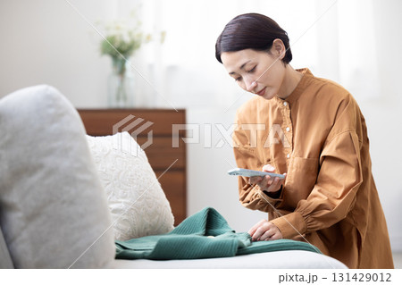 服をスマートフォンで撮影する女性 131429012