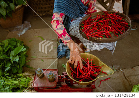 A vibrant market scene showcasing fresh, aromatic red chilies along with a local sellers stall 131429134