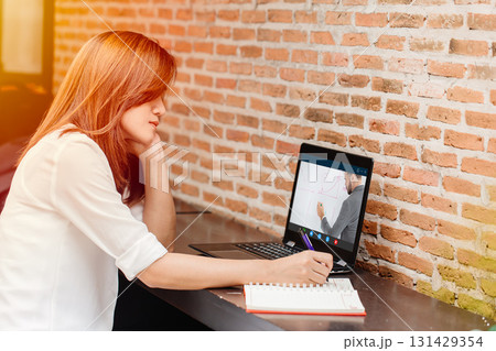 e-learning concept, woman watching teacher live internet video streaming lecture from laptop computer screen at cafe. e-learning concept, woman watching teacher live internet video streaming lecture from laptop computer screen at cafe. 131429354