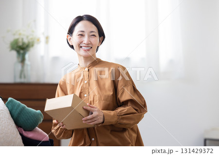 箱を持って微笑むミドル女性 131429372
