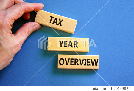 Tax year overview symbol. Concept words Tax year overview on beautiful wooden blocks. Beautiful blue background. Businessman hand. Business tax year overview concept. Copy space. 131429820