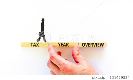 Tax year overview symbol. Concept words Tax year overview on beautiful wooden blocks. Beautiful white background. Businesswoman icon. Business tax year overview concept. Copy space. 131429824
