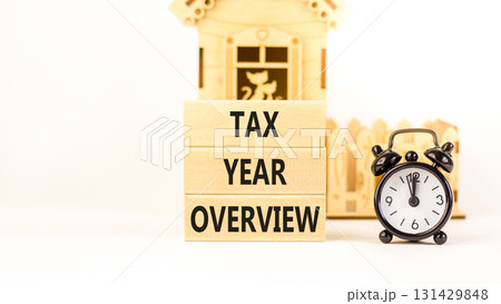 Tax year overview symbol. Concept words Tax year overview on beautiful wooden blocks. Beautiful white background. Black alarm clock. Business tax year overview concept. Copy space. 131429848