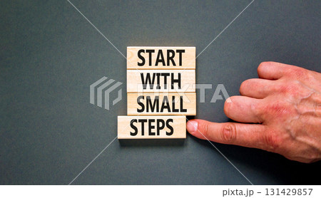 Start with small steps symbol. Concept words phrase Start with small steps on beautiful wooden blocks. Beautiful grey background. Businessman hand. Business Start with small steps concept. Copy space. 131429857