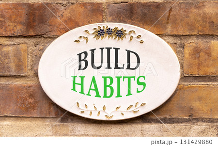 Build habits symbol. Concept word Build habits on beautiful white sign on brown old brick wall . Beautiful brown old brick wall background. Business build habits concept. Copy space. 131429880