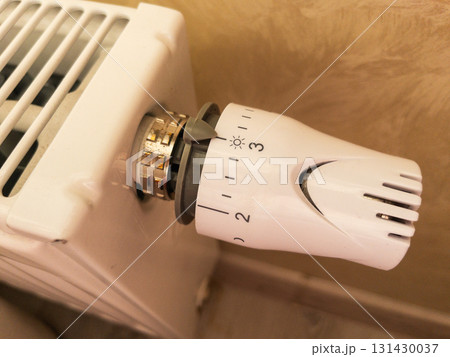 Close-up of a thermostatic radiator valve set to level three on a white panel heater. Concept of home heating, temperature control, and energy efficiency save on bills, improve comfort, and reduce Close-up of a thermostatic radiator valve set to level three on a white panel heater. Concept of home heating, temperature control, and energy efficiency save on bills, improve comfort, and reduce 131430037