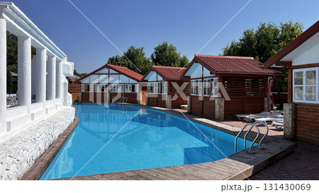 Resort complex with a swimming pool and wooden cottages on a summer day. 131430069