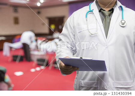 Doctor in gown uniform with stethoscope standing and holding chart in the quarantine room for the corona virus infected patients. Doctor in gown uniform with stethoscope standing and holding chart in the quarantine room for the corona virus infected patients. 131430394