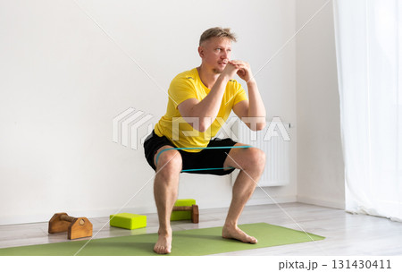 Sporty Young Man Doing Morning Squats In A Light Room Sporty Young Man Doing Morning Squats In A Light Room 131430411