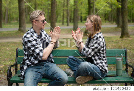 Father And Little Daughter Playing Clapping Game In Family Look While Sitting On A Bench Father And Little Daughter Playing Clapping Game In Family Look While Sitting On A Bench 131430420