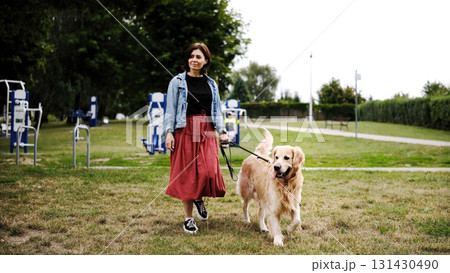 Girl Walks With A Golden Retriever In The Summer Park 131430490