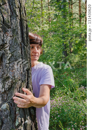 Mature woman enjoying nature and hugging pine tree in forest Mature woman enjoying nature and hugging pine tree in forest 131430620