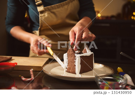 Home Chef Icing A Gingerbread House During Christmas Baking In A Cozy Kitchen Home Chef Icing A Gingerbread House During Christmas Baking In A Cozy Kitchen 131430950