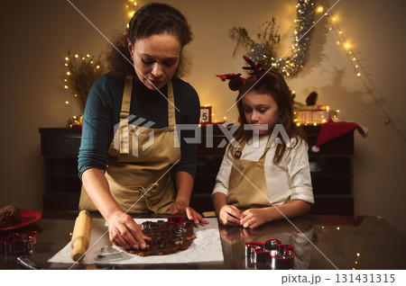 Mother And Daughter Bake Gingerbread House Together In A Cozy Christmas Kitchen 131431315