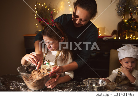 Joyful Mother Helps Daughter Bake Gingerbread With Son In Cozy Christmas Kitchen 131431468