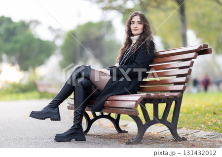 Young woman sitting on park bench looking 131432012