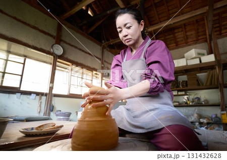 ろくろを使って器を形作る作務衣姿の女性 131432628