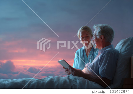 Young nurse holding tablet with elderly patient in bed under dreamy sunset sky in palliative care setting 131432974